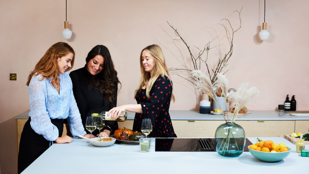 three women talking by kitchen island with wine